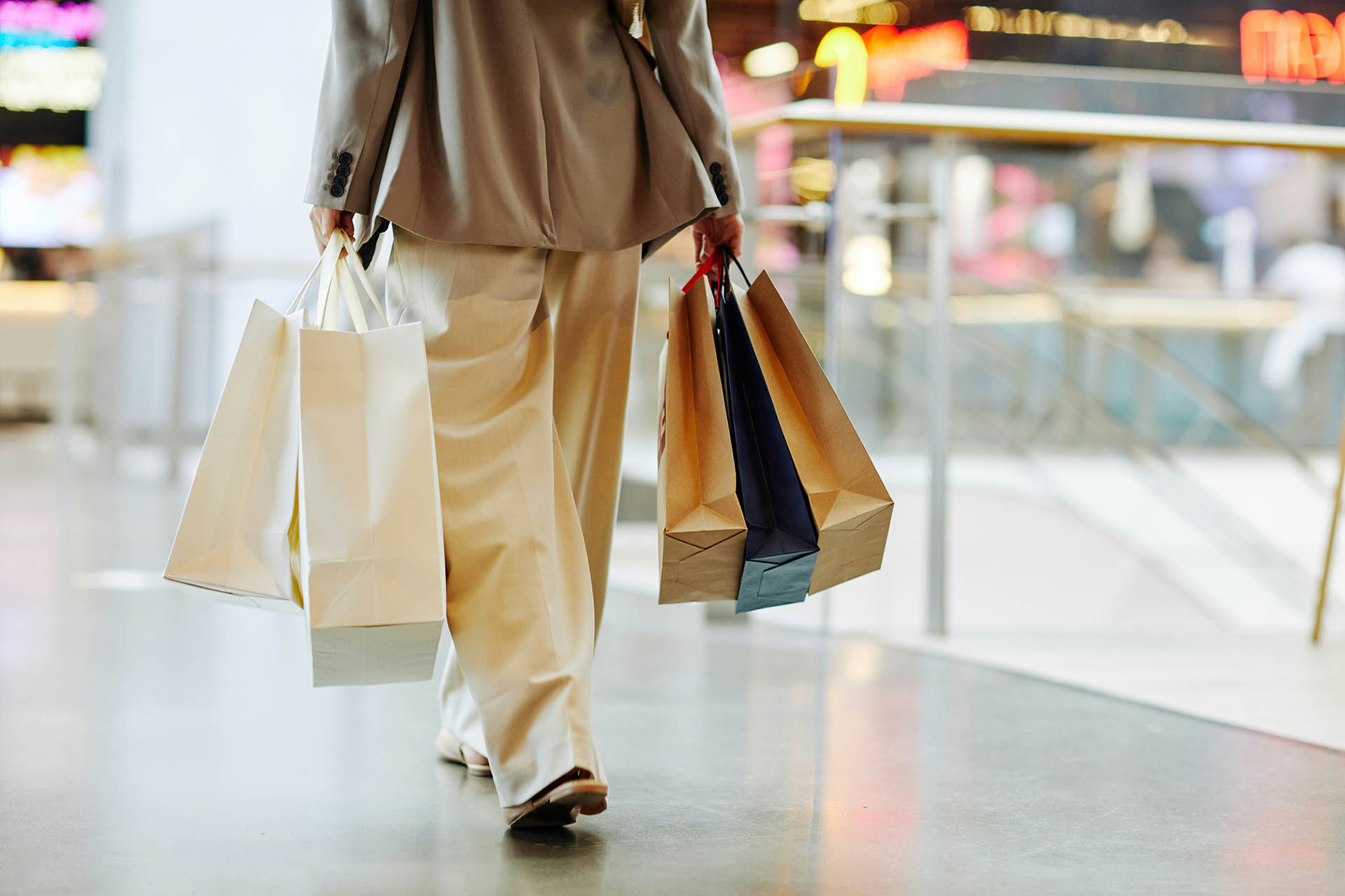 Person walking through shopping center with bags of purchases.
